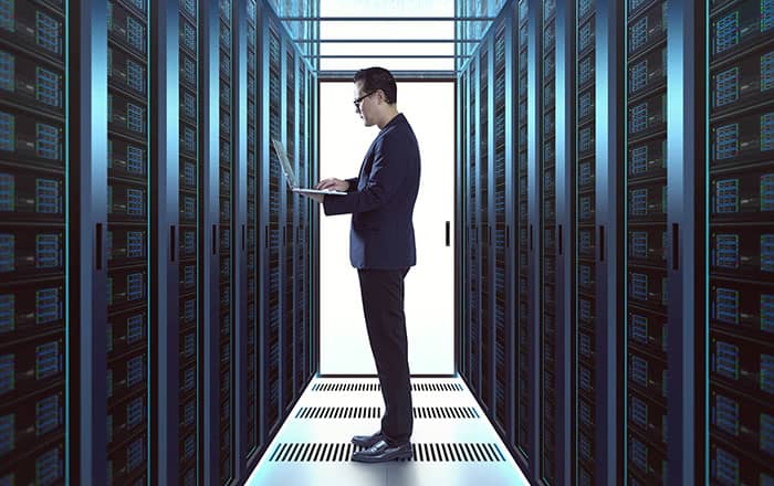 Man working on laptop inside a large server room